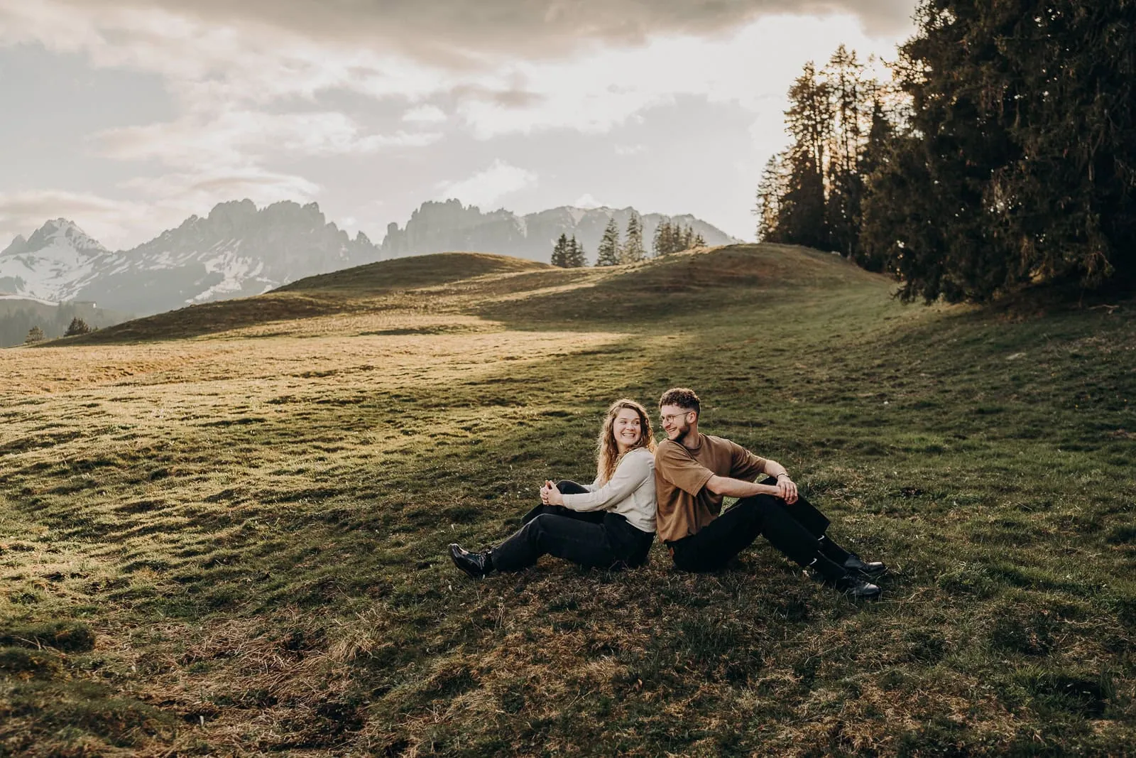 Couple assis dans un paysage montagneux ensoleillé.
