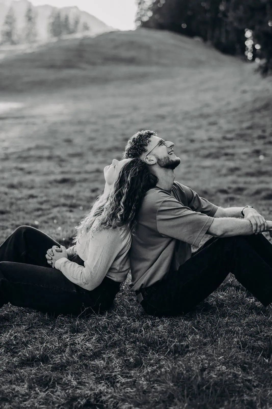 Couple assis dos à dos dans un pré