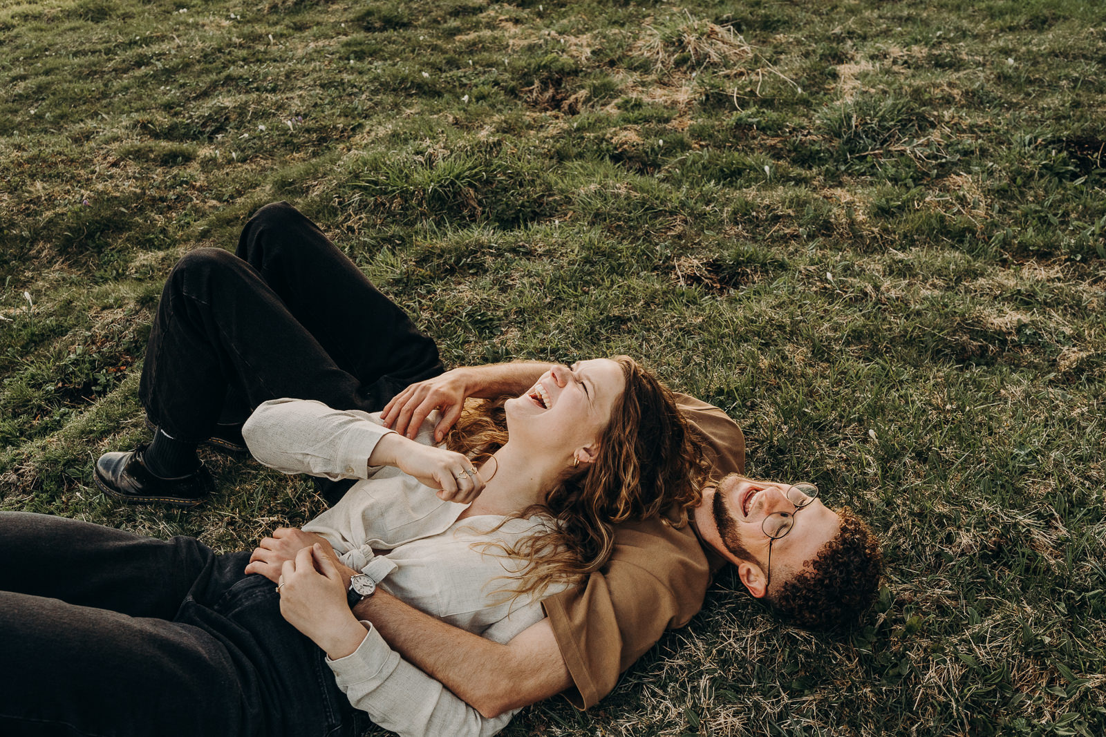 Couple allongé sur l'herbe, riant ensemble.