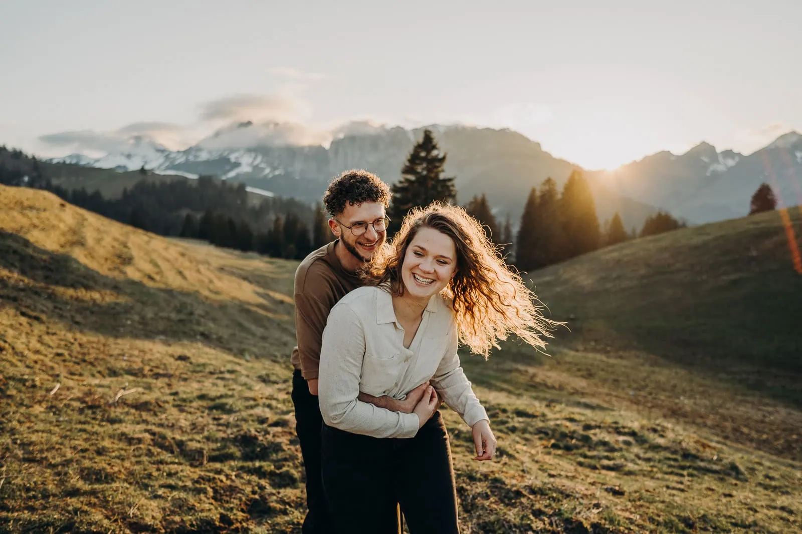 Couple souriant dans la montagne au coucher du soleil.