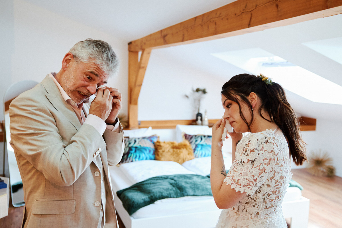 Mariée et homme émus dans une chambre lumineuse.