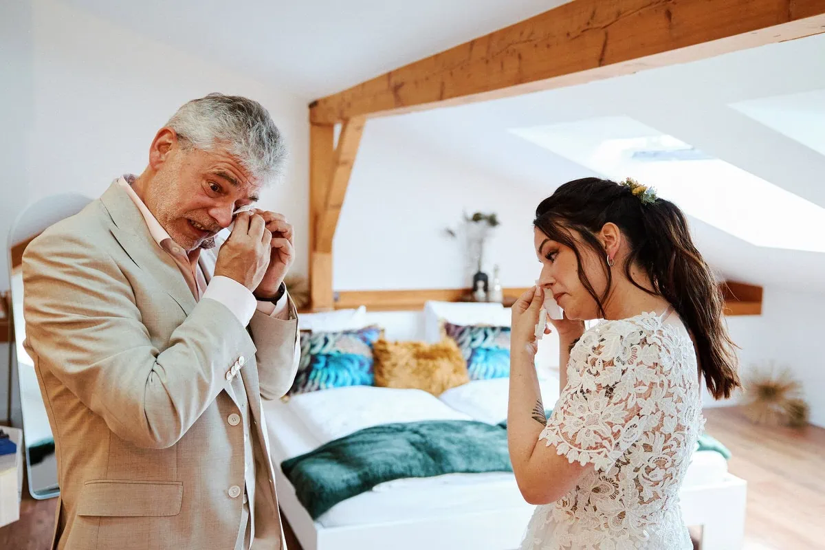 Mariée et homme émus dans une chambre lumineuse.