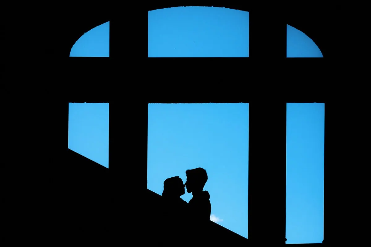 Silhouettes de couple dans une grande fenêtre bleue.