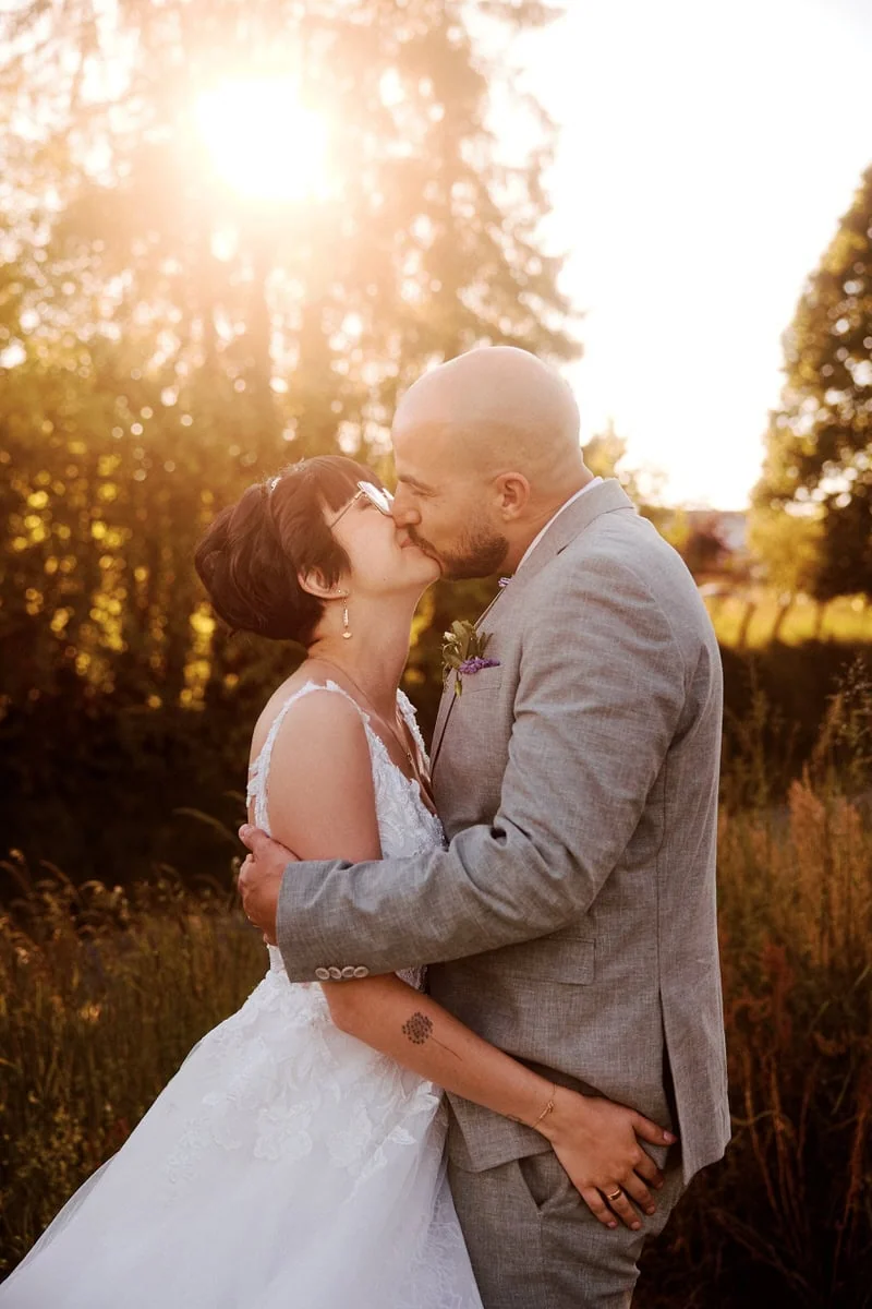 Mariage couple s'embrassant au coucher du soleil.