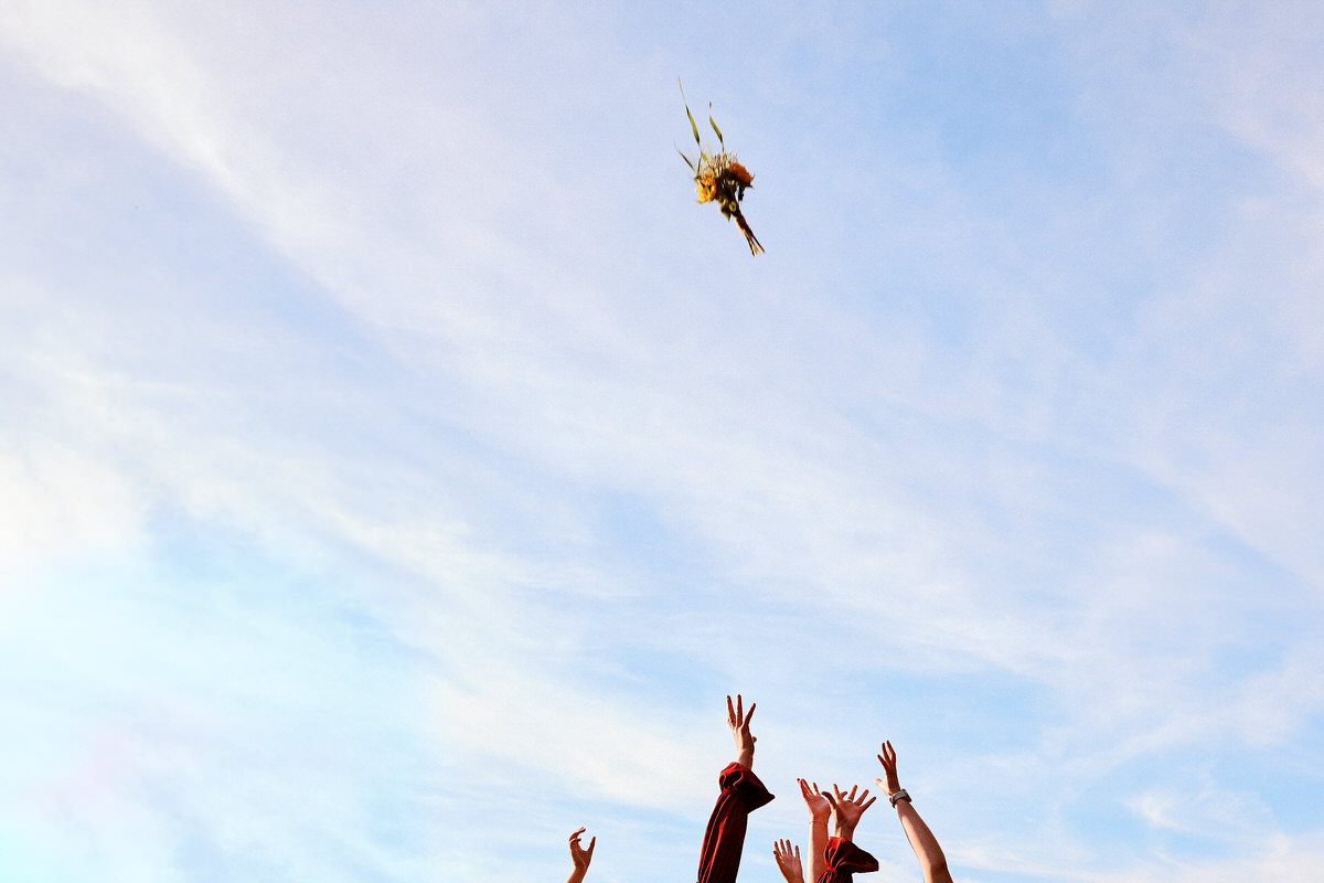 Mains tendues vers un bouquet volant dans le ciel.