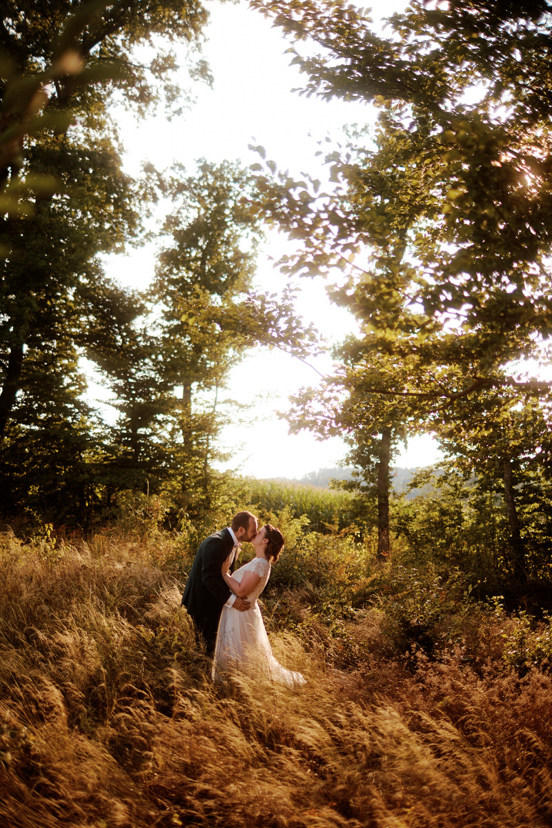 Couple s'embrassant dans une forêt ensoleillée.