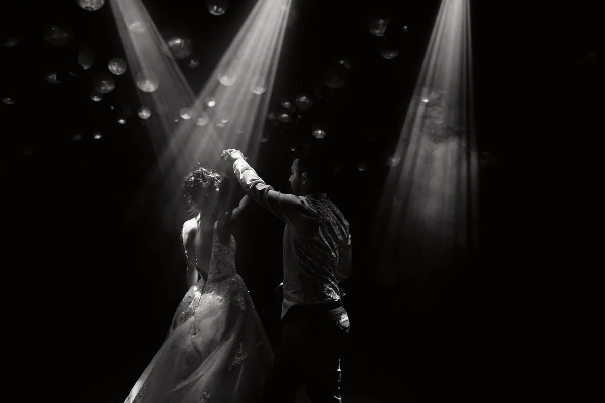Couple dansant sous les lumières, ambiance romantique.