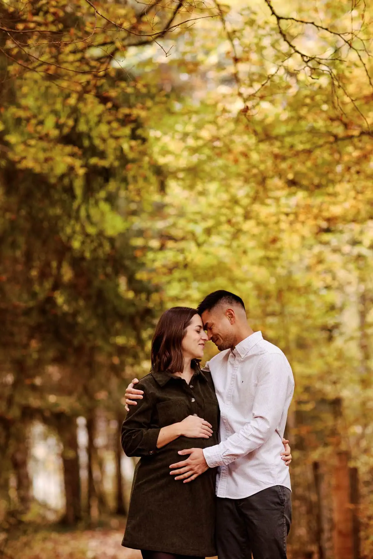 Couple s'enlace tendrement dans une forêt automnale.