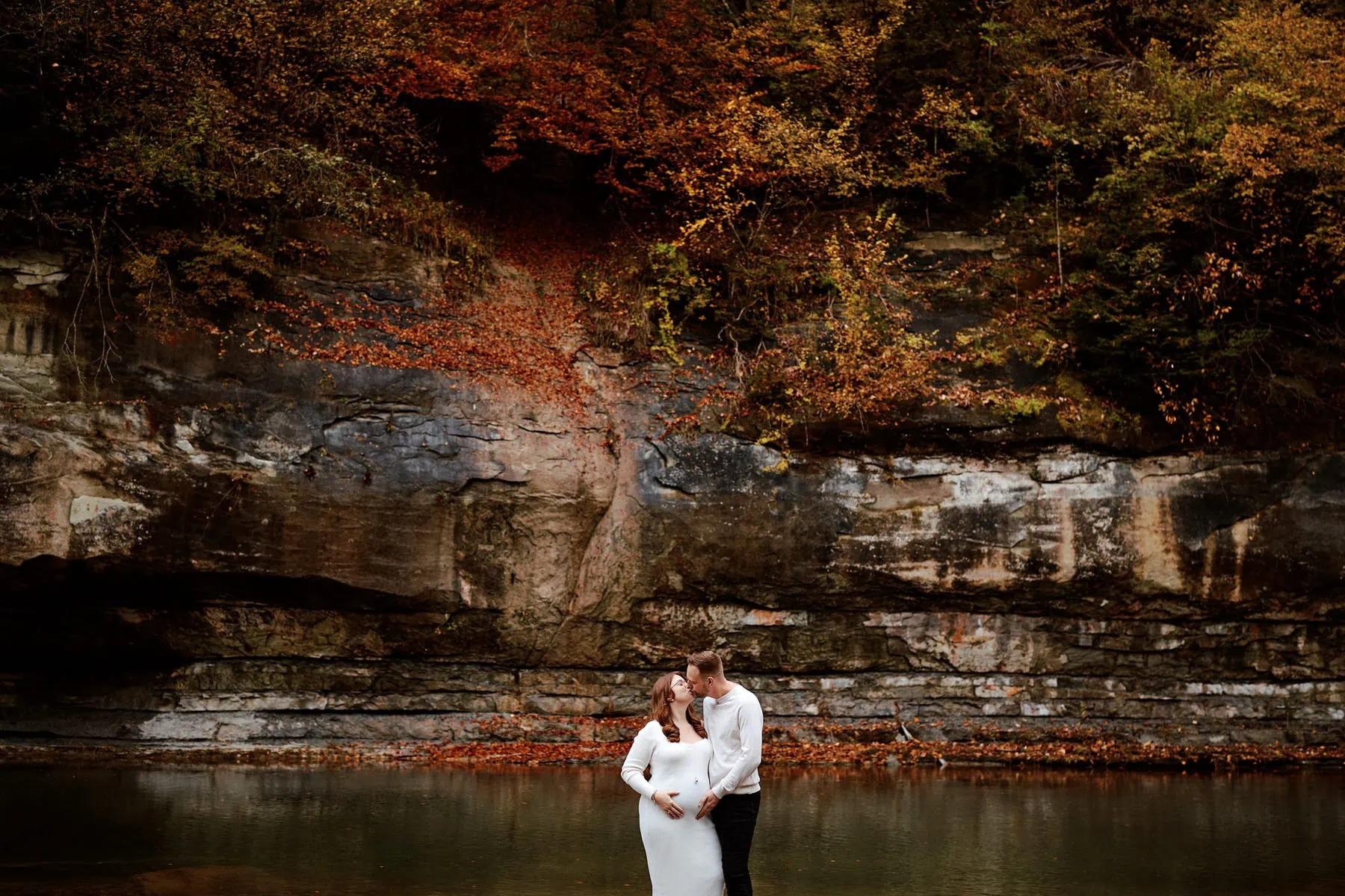 Couple s'embrassant devant une falaise automnale.