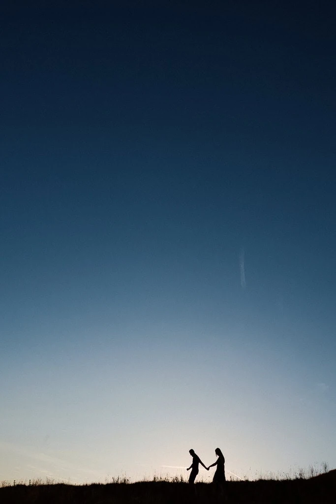 Silhouette d'un couple marchant main dans la main au coucher du Soleil