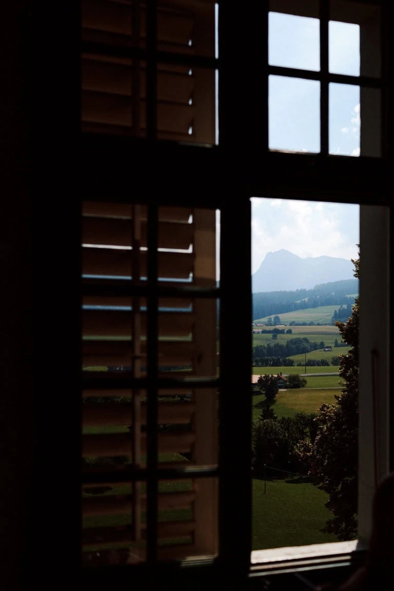 Vue de montagne par une fenêtre ombragée.