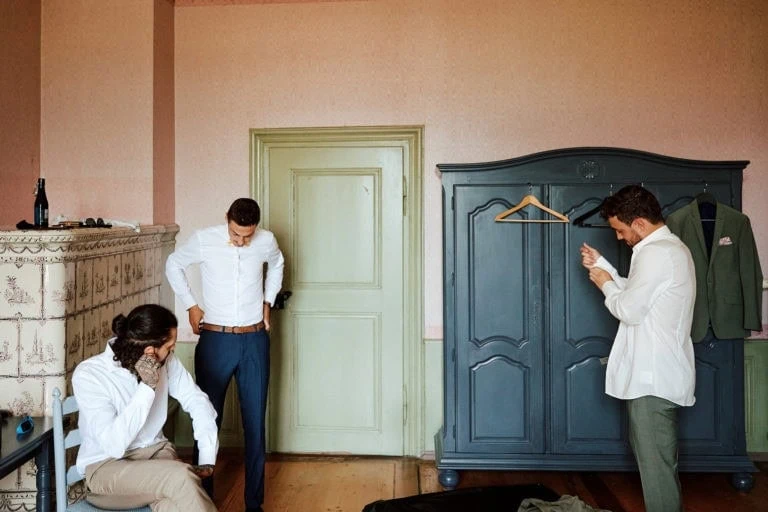 Trois hommes habillés dans une chambre.