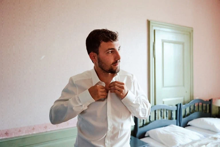 Homme boutonner chemise blanche dans chambre.