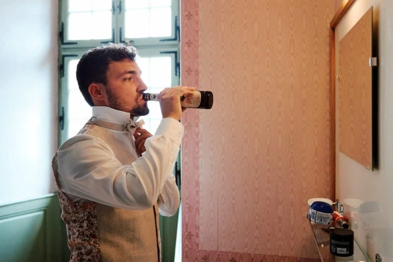 Homme habillé buvant une bière.