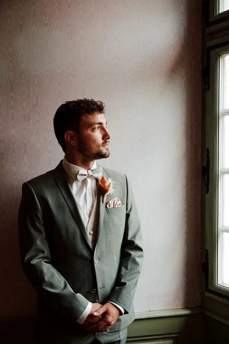 Homme élégant en costume regardant par la fenêtre.