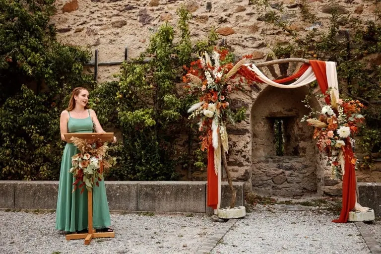 Discours de mariage devant l'arche fleurie extérieure.