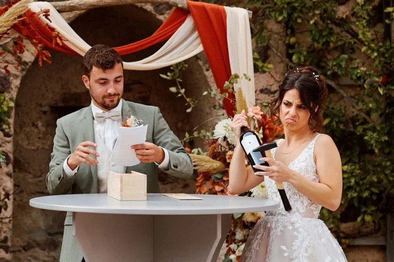 Mariée confuse ouvrant bouteille, marié lisant discours