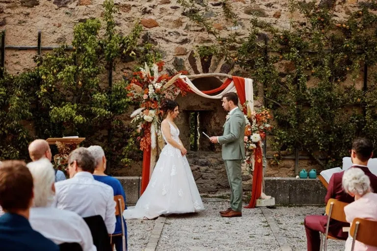 Cérémonie de mariage en extérieur avec arche fleurie.