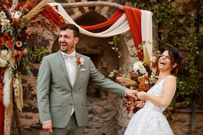 Mariage heureux avec rires et fleurs colorées.