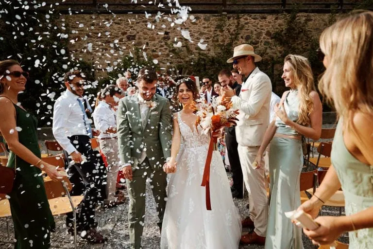 Mariage, couple souriant sous pluie de confettis.