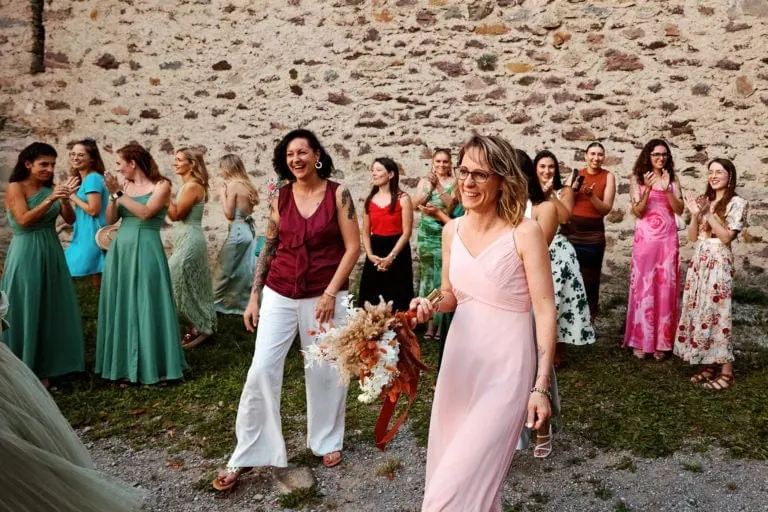Femmes souriantes en robes élégantes devant un mur.