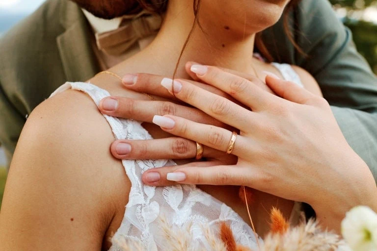 Mains avec alliances sur robe en dentelle.