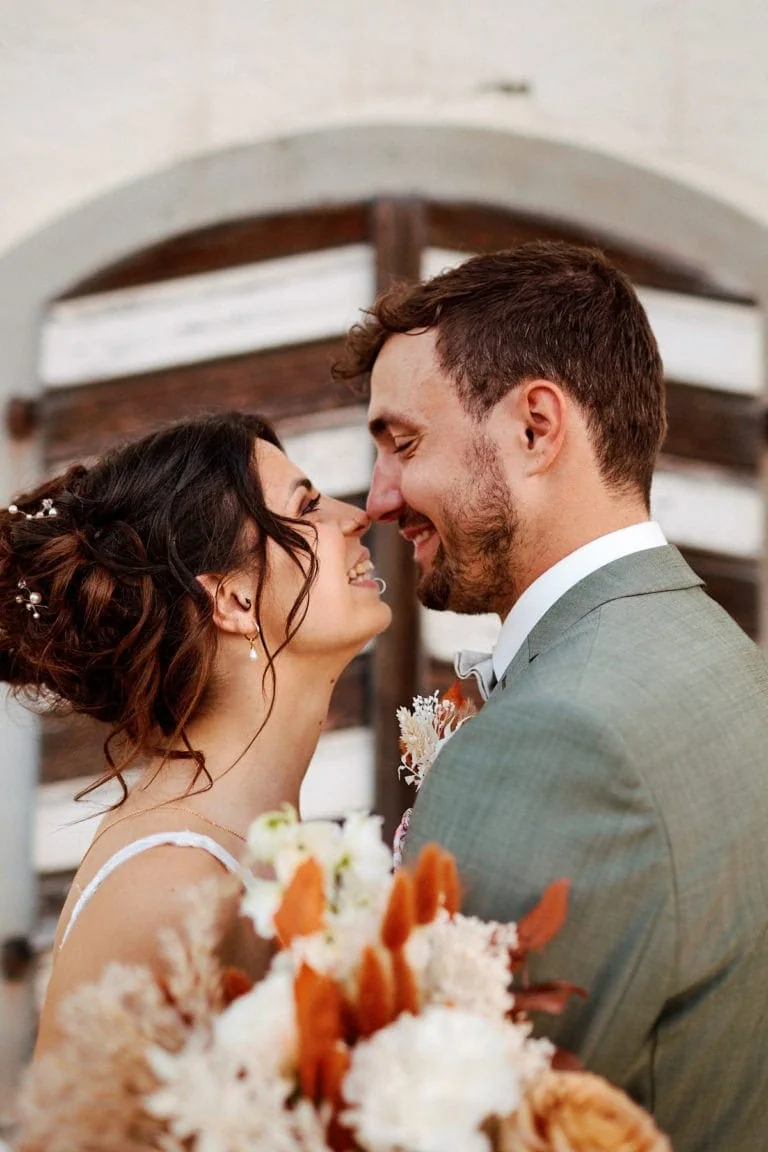 Couple souriant avec bouquet de mariage, rapprochés.