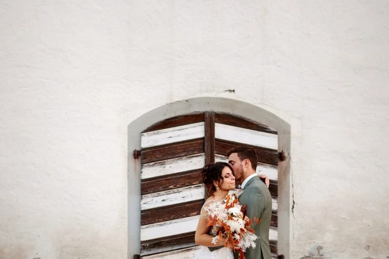 Couple embrassé devant ancienne porte en bois.