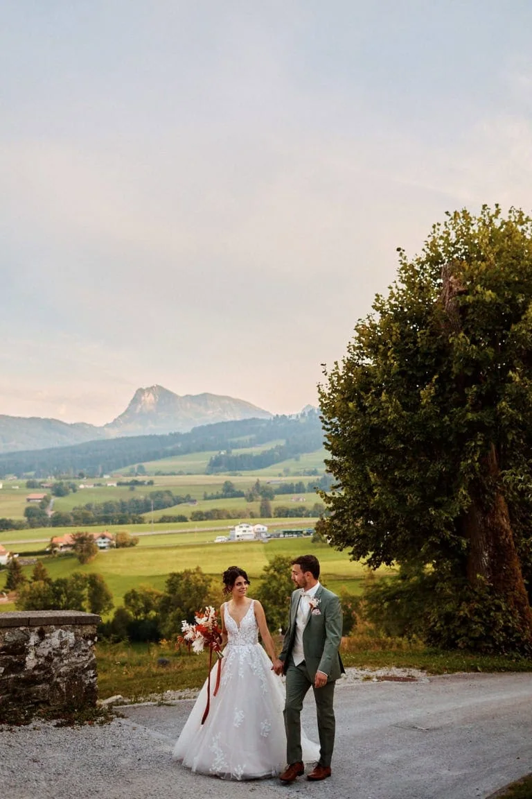 Couple marié marchant dans paysage rural montagneux.