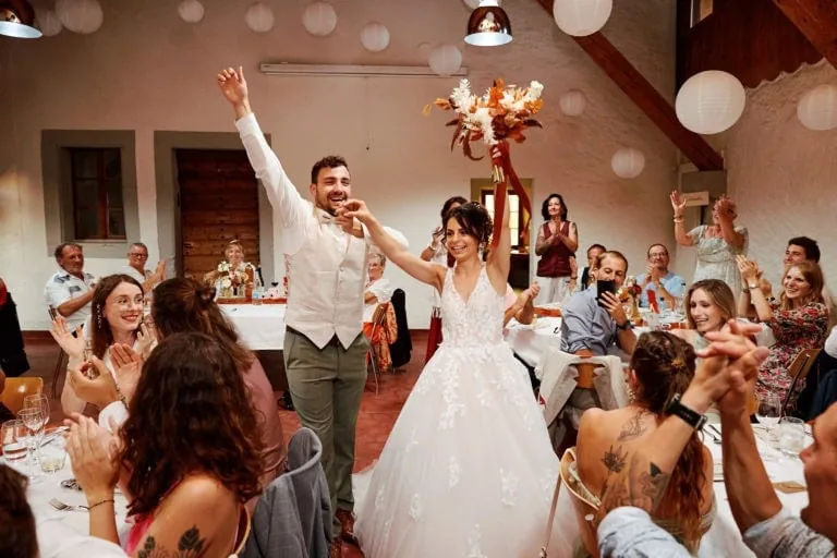 Mariage, couple souriant entouré d'invités applaudissant.