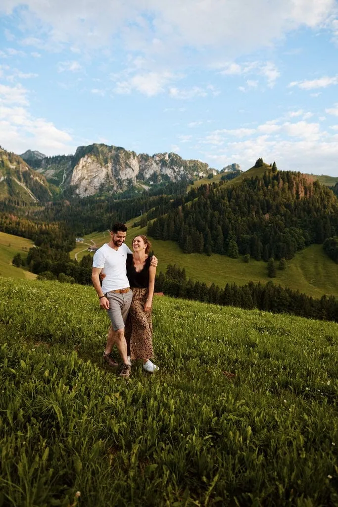 Couple marchant dans un paysage montagnard verdoyant.