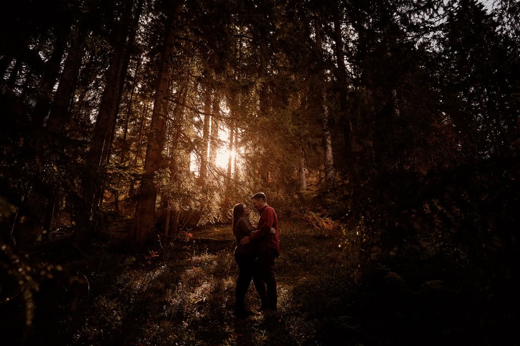Couple embrassant dans une forêt ensoleillée.