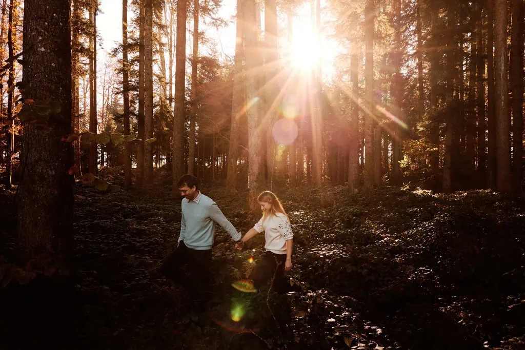 Couple marchant à travers une forêt ensoleillée.