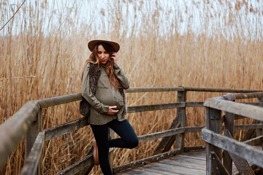 Femme enceinte posant sur une promenade en bois.