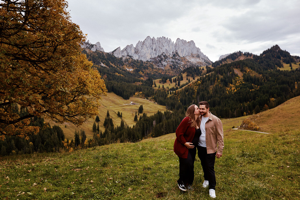 Couple s'embrassant devant montagnes automnales.