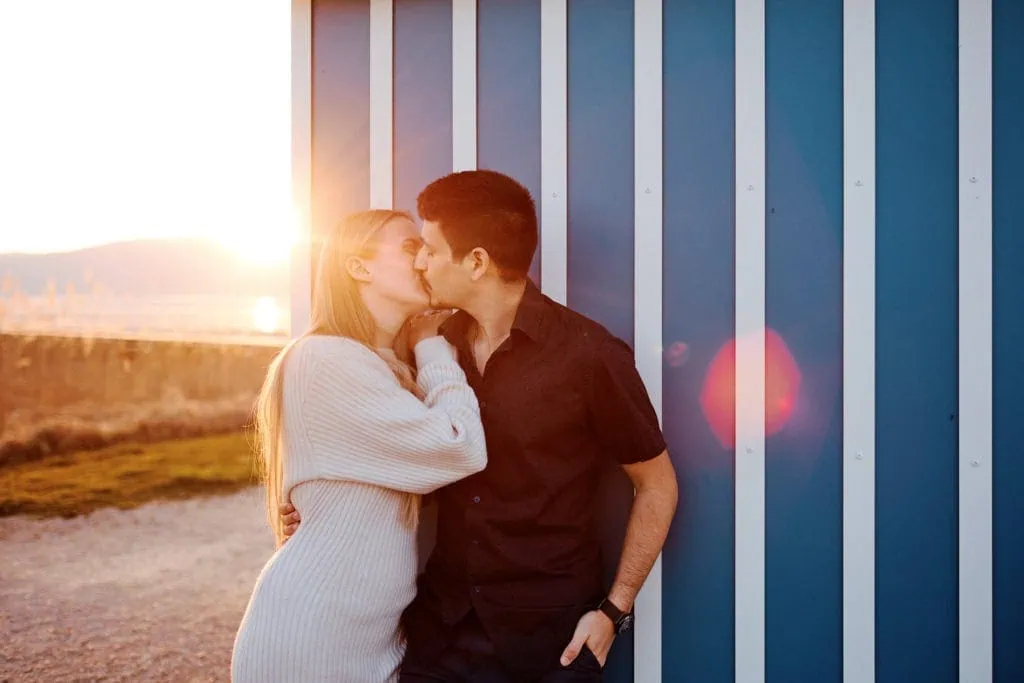 Couple s'embrassant devant un mur bleu au coucher.