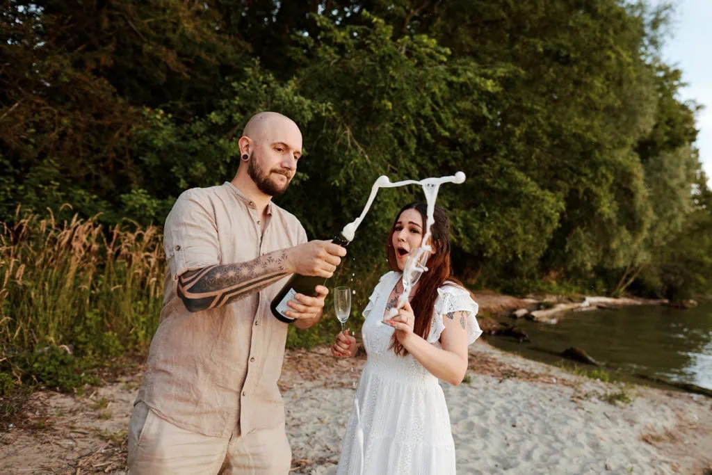 Couple ouvre du champagne sur la plage.