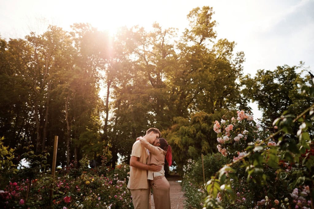 Couple s'embrassant dans un jardin fleuri, lumière douce.