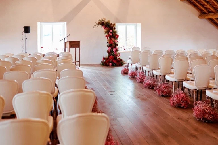 Salle de cérémonie décorée avec des chaises blanches.