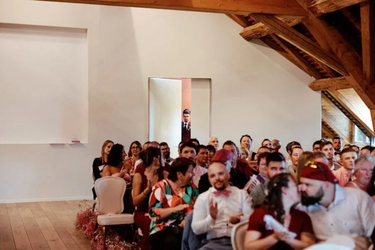 Homme en costume entrant, invités applaudissent.