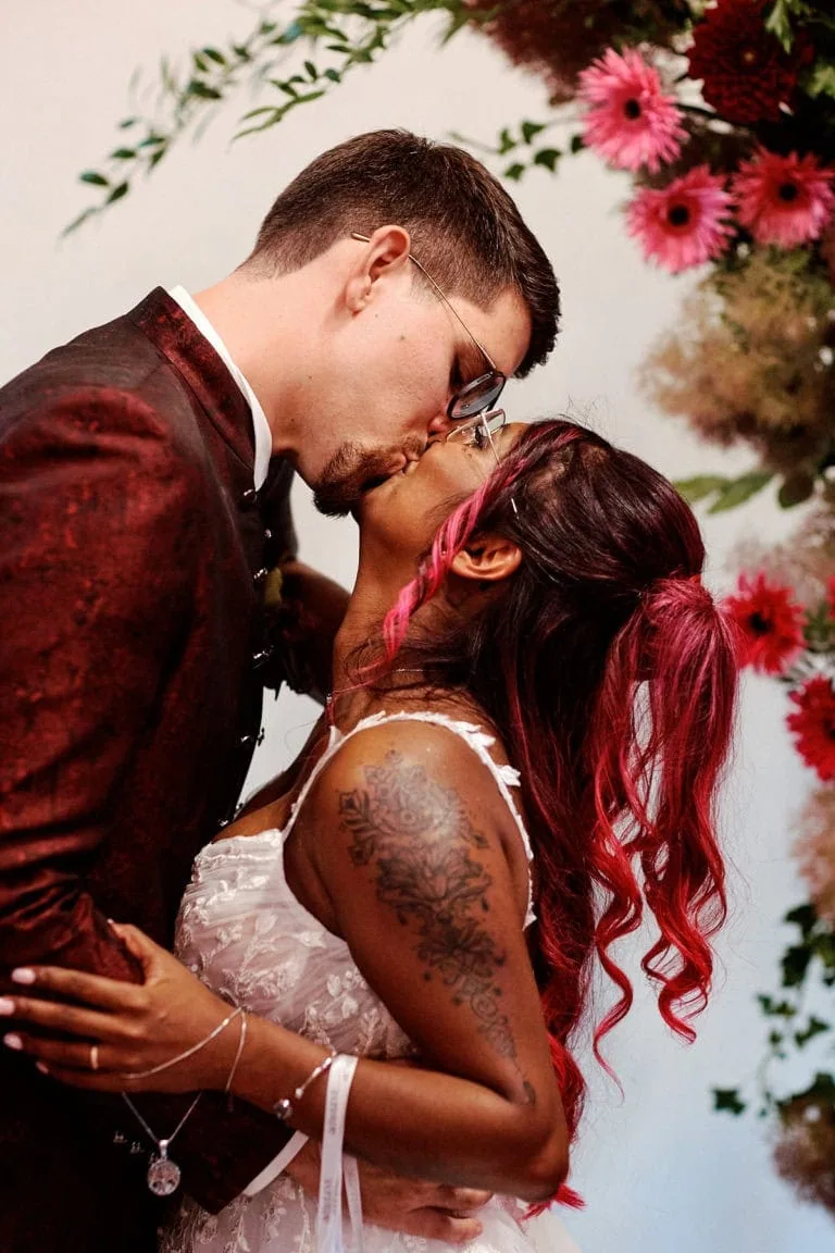 Couple s'embrassant lors d'un mariage avec des fleurs roses.