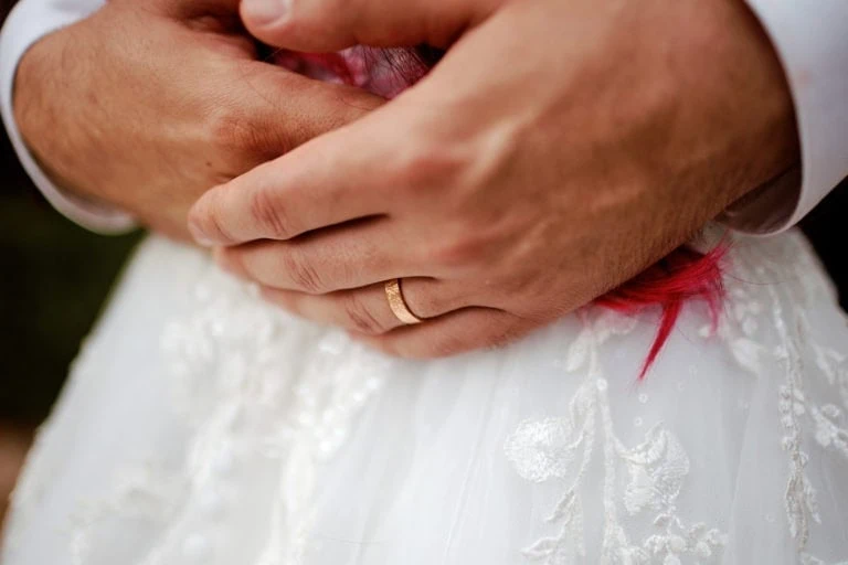 Mains avec alliance sur robe blanche