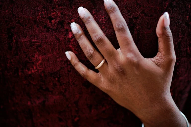 Main avec alliance sur fond rouge.