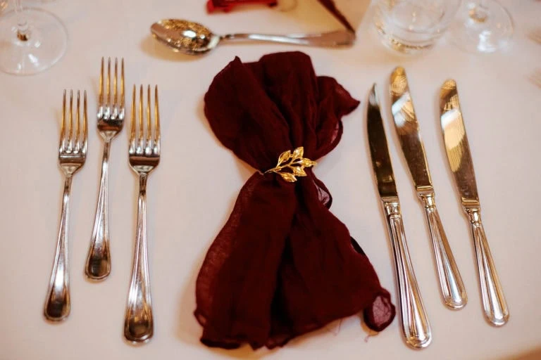 Couverts élégants sur nappe blanche avec serviette rouge.