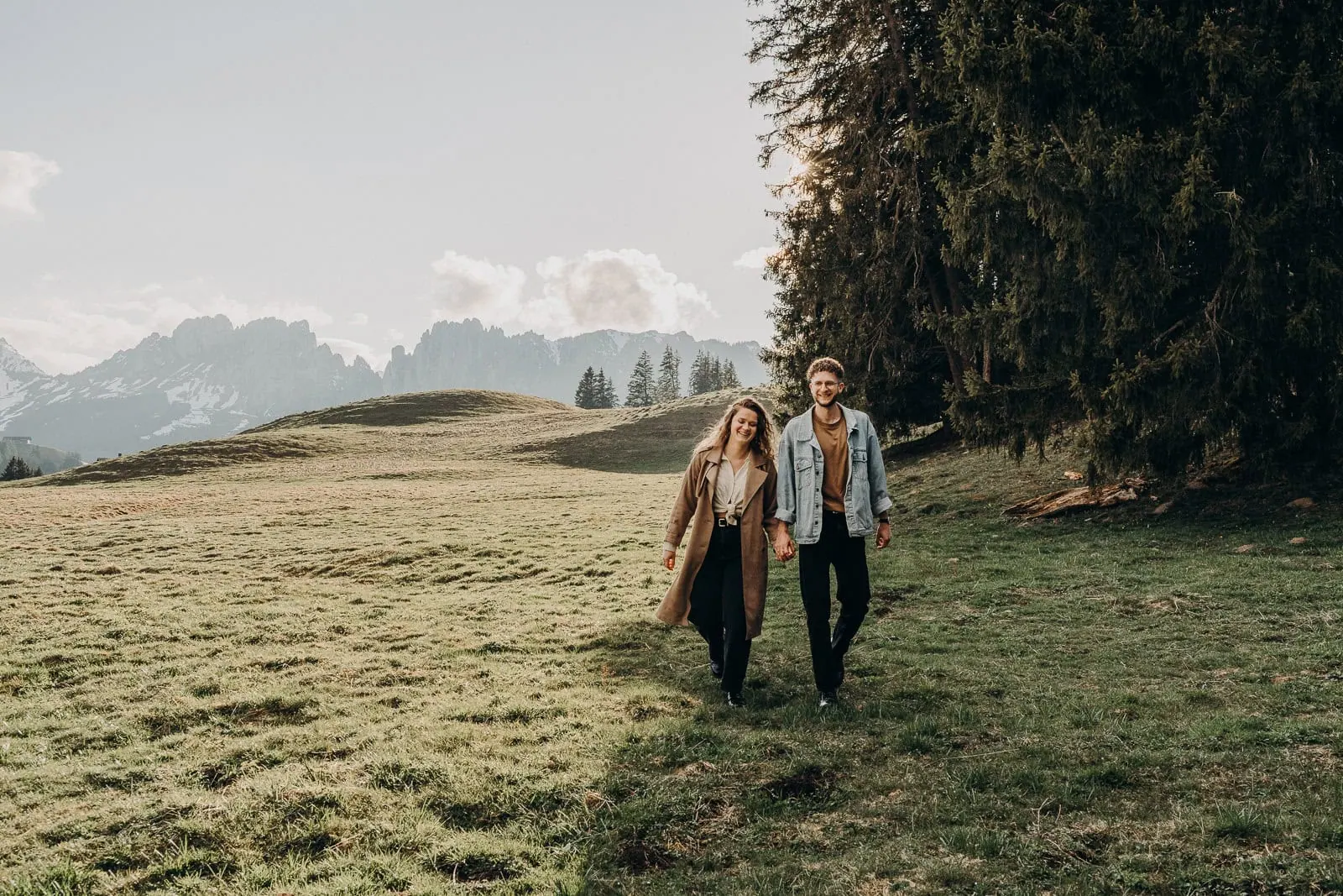 Couple marchant dans un paysage montagneux ensoleillé.