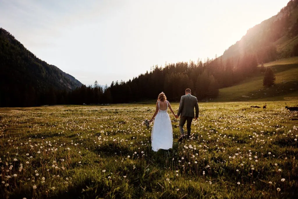 Couple marchant dans un champ au coucher du soleil.