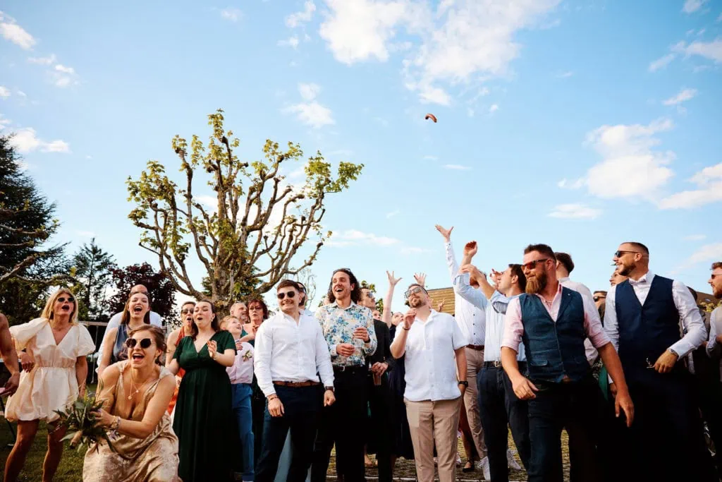 Lancer de bouquet, les invités tendent les mains vers le bouquet dans le ciel.