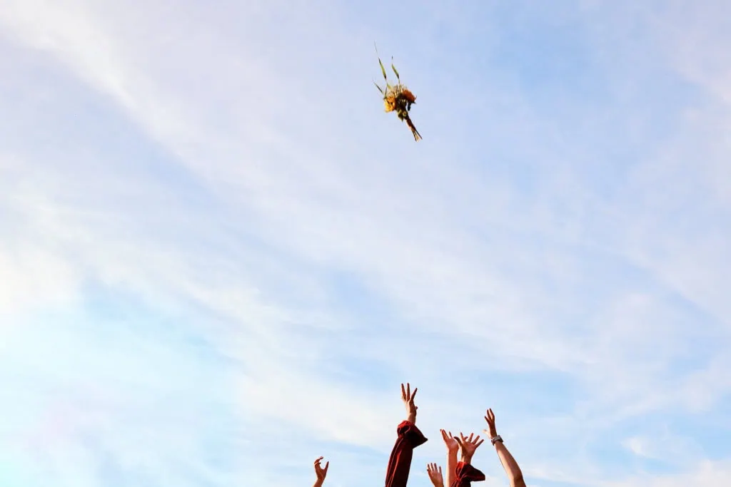 Lancer de bouquet, les invités tendent les mains vers le bouquet dans le ciel.