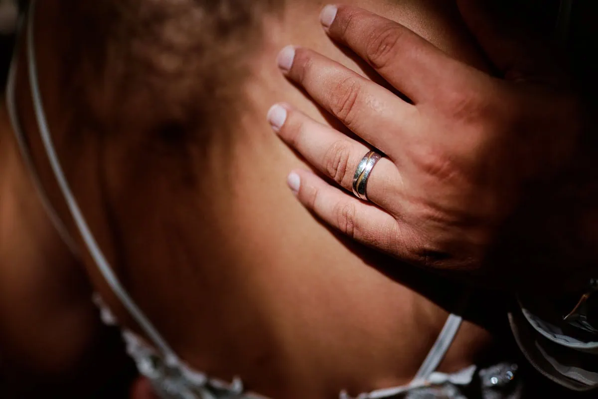 Main portant une alliance sur une épaule nue