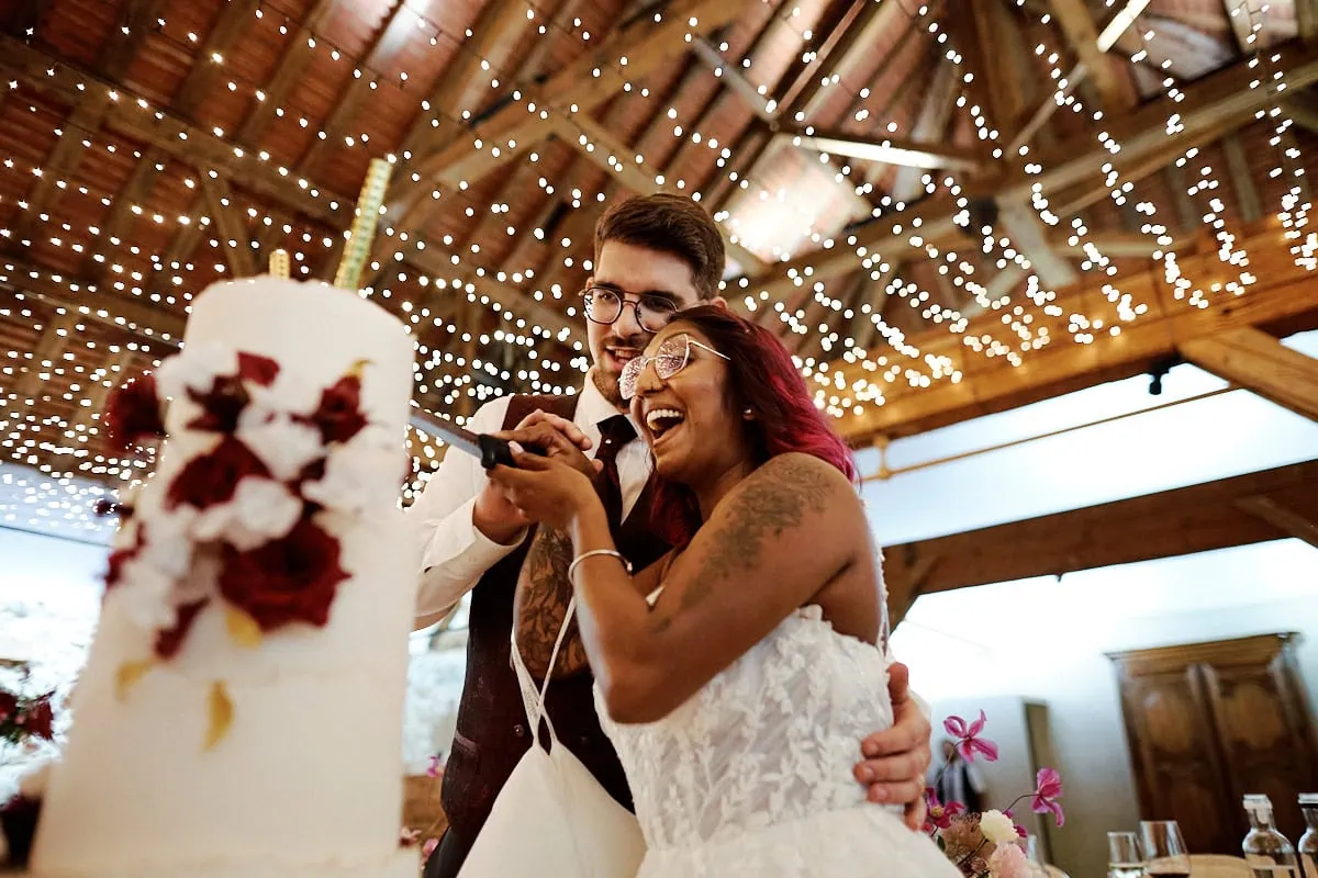 Photographe professionnel capture un mariage joyeux avec couple souriant devant un gâteau de mariage.